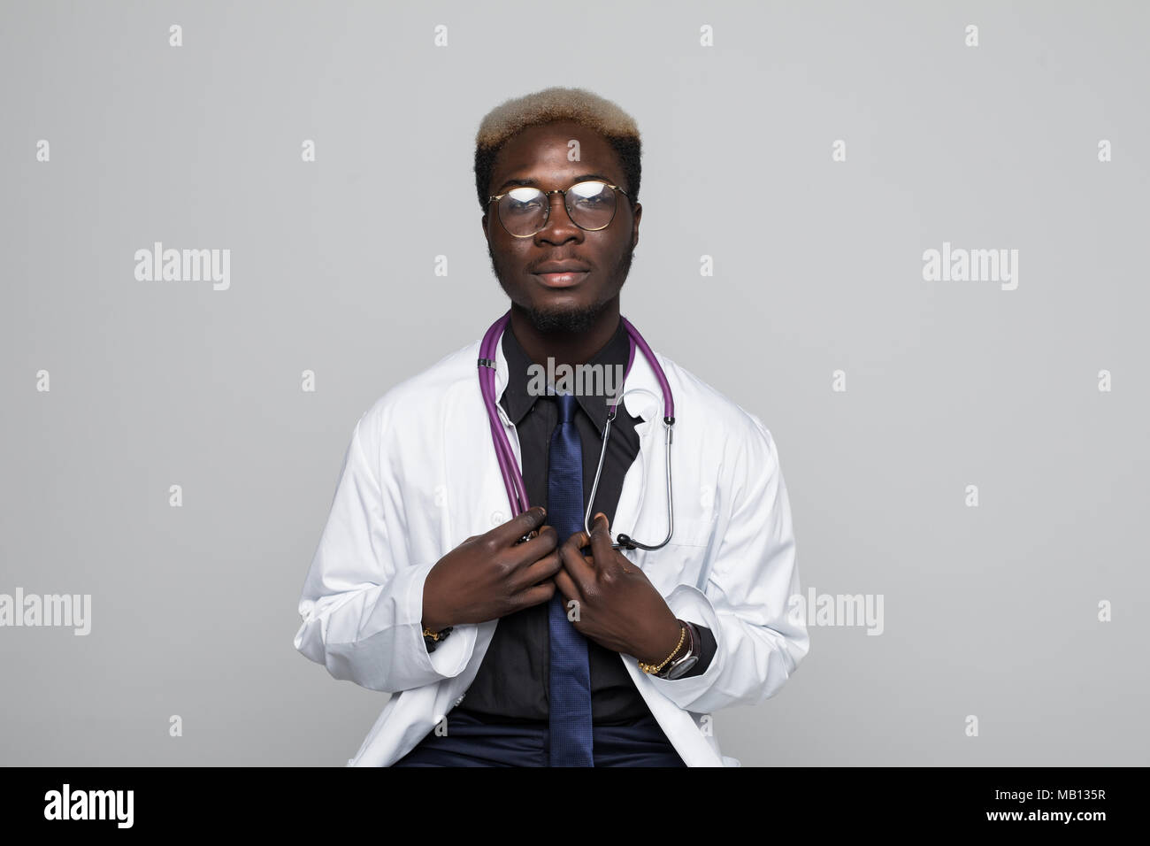 Portrait médecin noir assis sur une chaise isolée sur gray Banque D'Images Portrait médecin noir assis sur une chaise isolée sur gray Banque D'Images