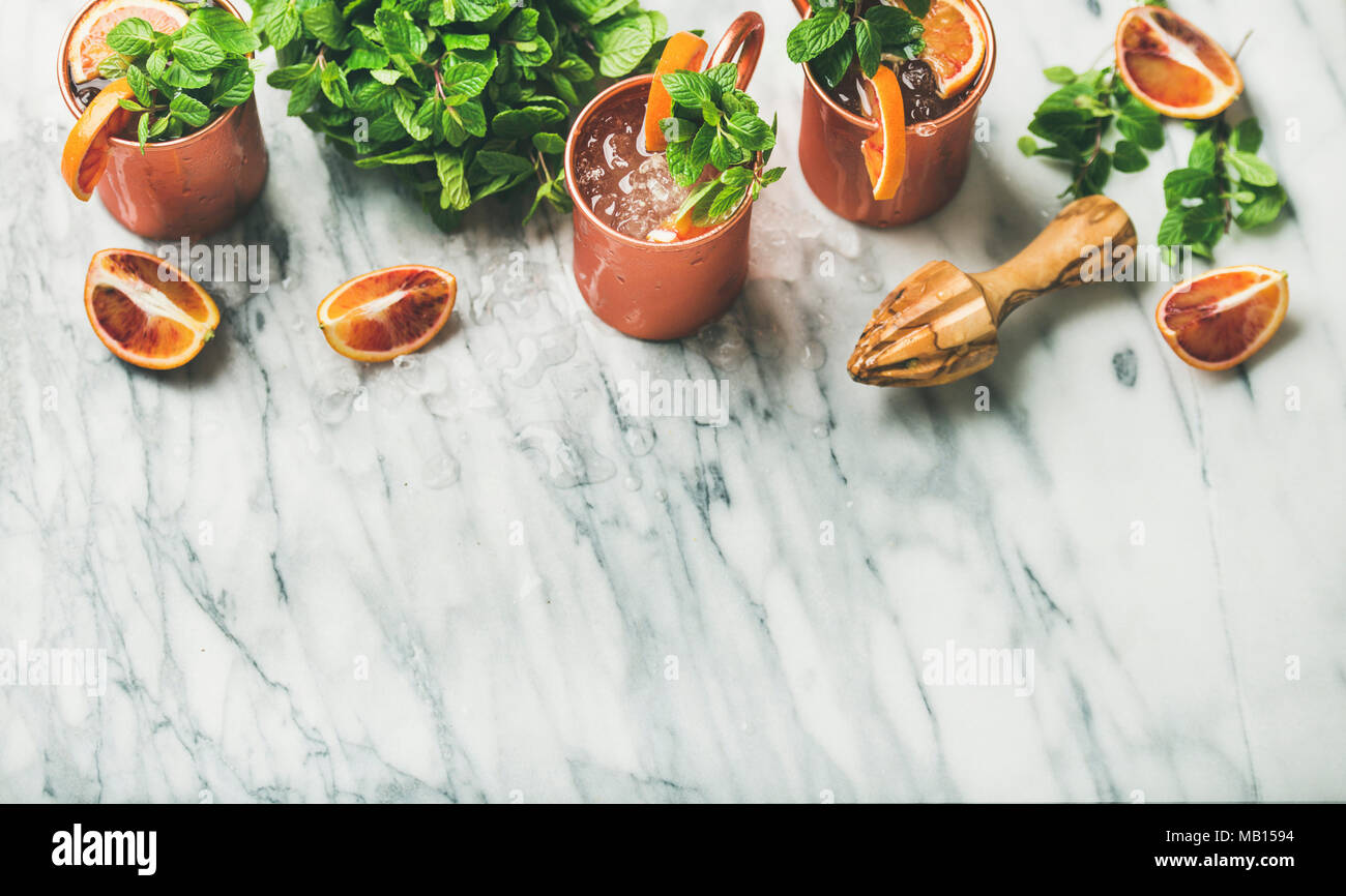 Orange sanguine mule de Moscou avec des cocktails d'alcool de menthe fraîche et de la glace dans des tasses en cuivre sur fond de marbre blanc, copy space Banque D'Images