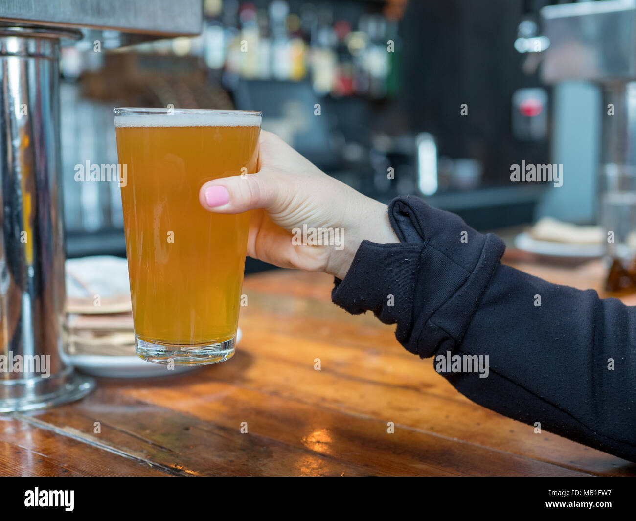 Femme soulevant pint verre de bière dans un bar de l'IPA dans une brasserie Banque D'Images