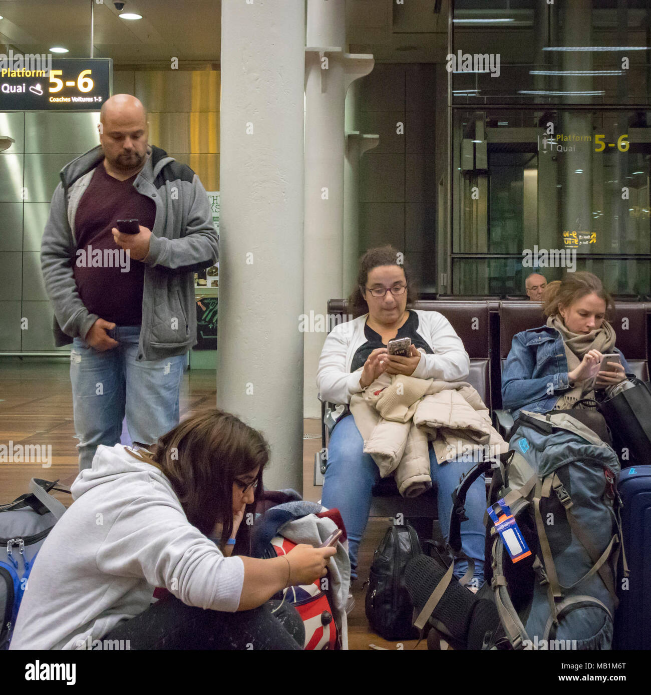 Les gens dans la salle d'attente de l'Eurostar de St Pancras, Londres, Angleterre, tous à l'aide de leur téléphone mobile Banque D'Images