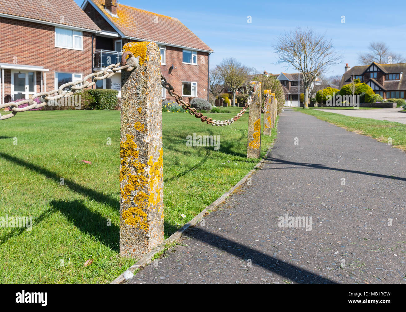 Poster et la chaîne de sécurité faible barrière à l'extrémité d'un jardin à l'avant avec des poteaux en béton couverts de mousse, d'un pavement en Angleterre, Royaume-Uni Banque D'Images