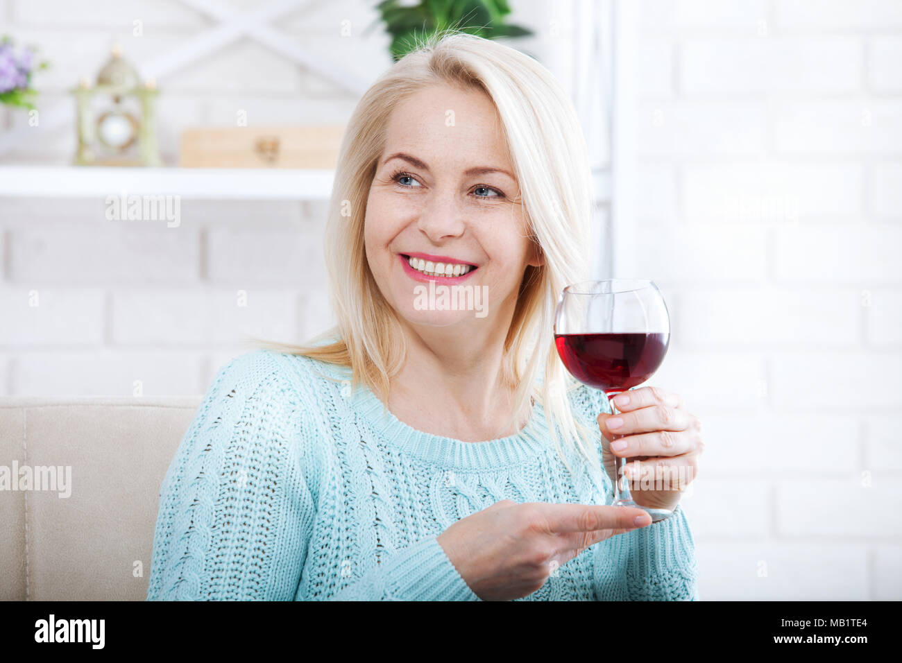 Happy blonde boire du vin rouge avec les yeux fermés. Banque D'Images