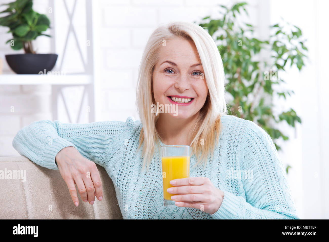 Smiling Woman drinking orange juice. Beau modèle de race blanche d'âge moyen face closeup. Banque D'Images