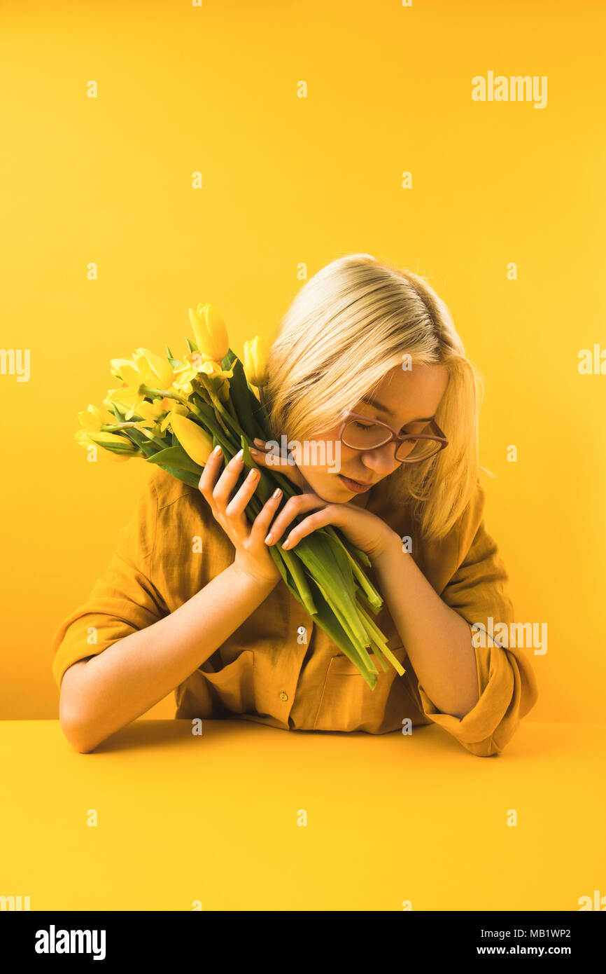 Belle Jeune femme tenant des fleurs de printemps jaune sur jaune Banque D'Images