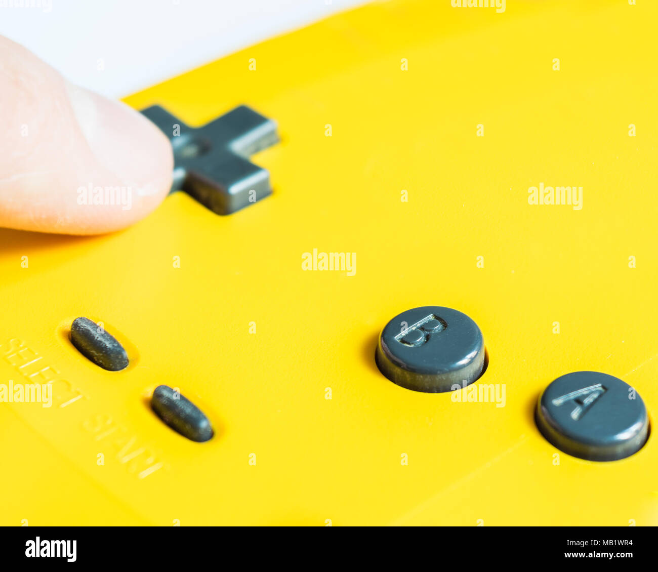 Doigt sur les boutons d'une manette de jeu vidéo jaune Banque D'Images Doigt sur les boutons d'une manette de jeu vidéo jaune Banque D'Images