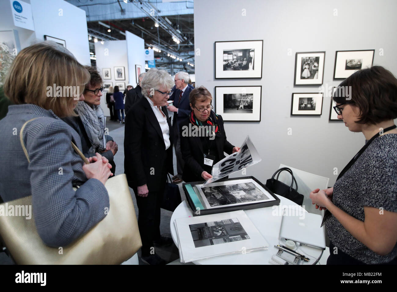 New York, USA. 5ème apr 2018. Un représentant de l'exposant (C) montre la photographie travaille aux visiteurs à AIPAD (Association of International Photography Art Dealers)'s la photographie à New York, États-Unis, le 5 avril 2018. La 38e édition de la photographie se tiendra du 5 avril au 8 avril. Environ 100 des plus grands fine art photography galeries présentent une gamme de travaux, y compris de qualité musée contemporain, moderne, et des photographies du xixe siècle, ainsi qu'une photographie, d'art vidéo et nouveaux médias. Credit : Wang Ying/Xinhua/Alamy Live News Banque D'Images