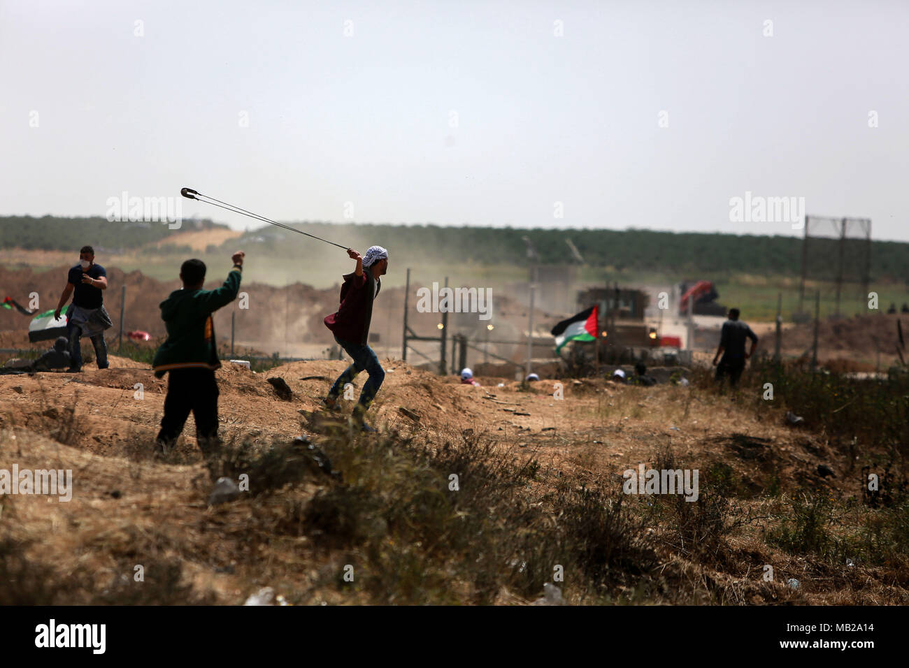 (180406) -- GAZA, 6 avril 2018 (Xinhua) -- un manifestant palestinien utilise une fronde pour lancer des pierres sur des soldats israéliens lors d'affrontements sur la frontière Gaza-Israel, est de la ville de Gaza, le 6 avril 2018. Des centaines de manifestants palestiniens ont commencé vendredi pour mettre le feu à des dizaines de pneus de voiture près de la frontière entre l'est de Gaza et Israël dans une tentative de rendre un bouclier de fumée noire pour se protéger des tirs des soldats israéliens. (Xinhua/Stringer) (ZF) Banque D'Images