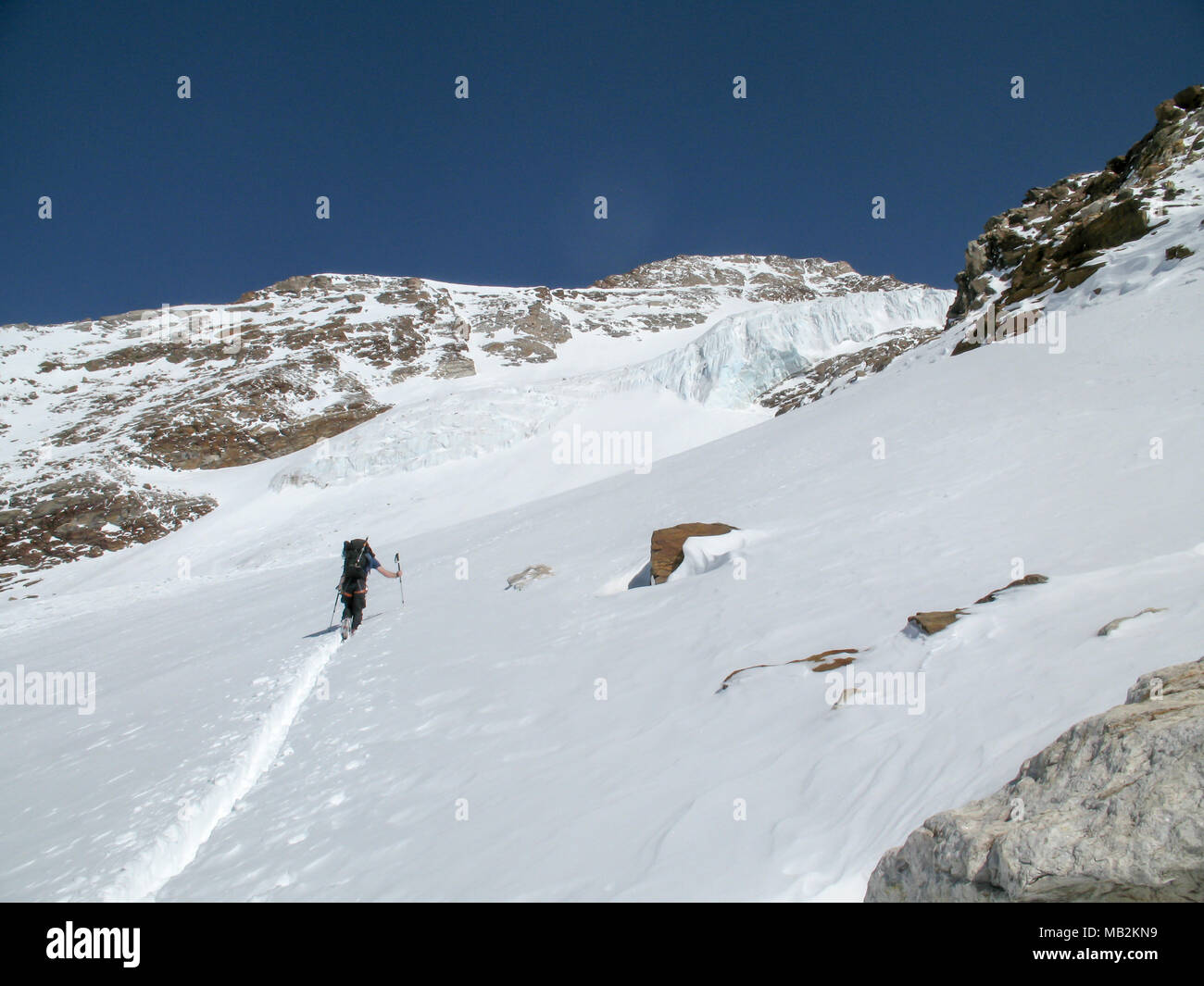 Homme de l'arrière-pays sur une tour de ski skieur mettre premiers morceaux sur son chemin à un haut sommet alpin dans les montagnes du Mont Rose dans la neige très profonde Banque D'Images