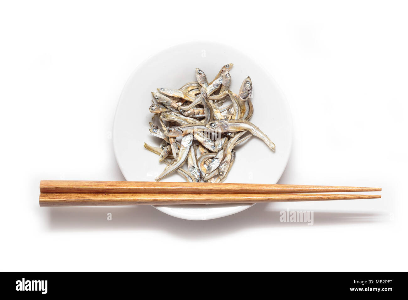 Séché japonaise avec des baguettes en bois sardine nourrisson isolé sur fond blanc. La cuisine japonaise. Collation santé alimentation. Niboshi Iriko ou poisson. Banque D'Images