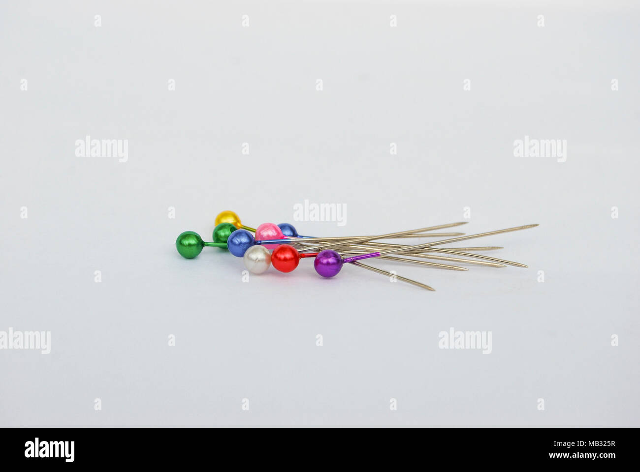 Goupilles avec têtes rondes multicolores, isolé sur un fond gris. Banque D'Images