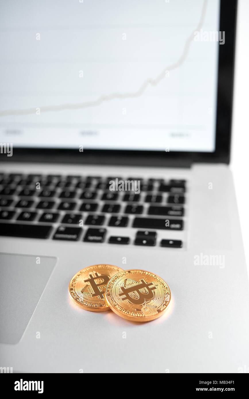 Deux golden bitcoins comme cryptocurrencies principal d'argent placé sur un ordinateur portable avec écran graphique de flou sur l'arrière-plan. La monnaie électronique de l'argent virtuel numérique blockchain tendance future banque innovante Banque D'Images