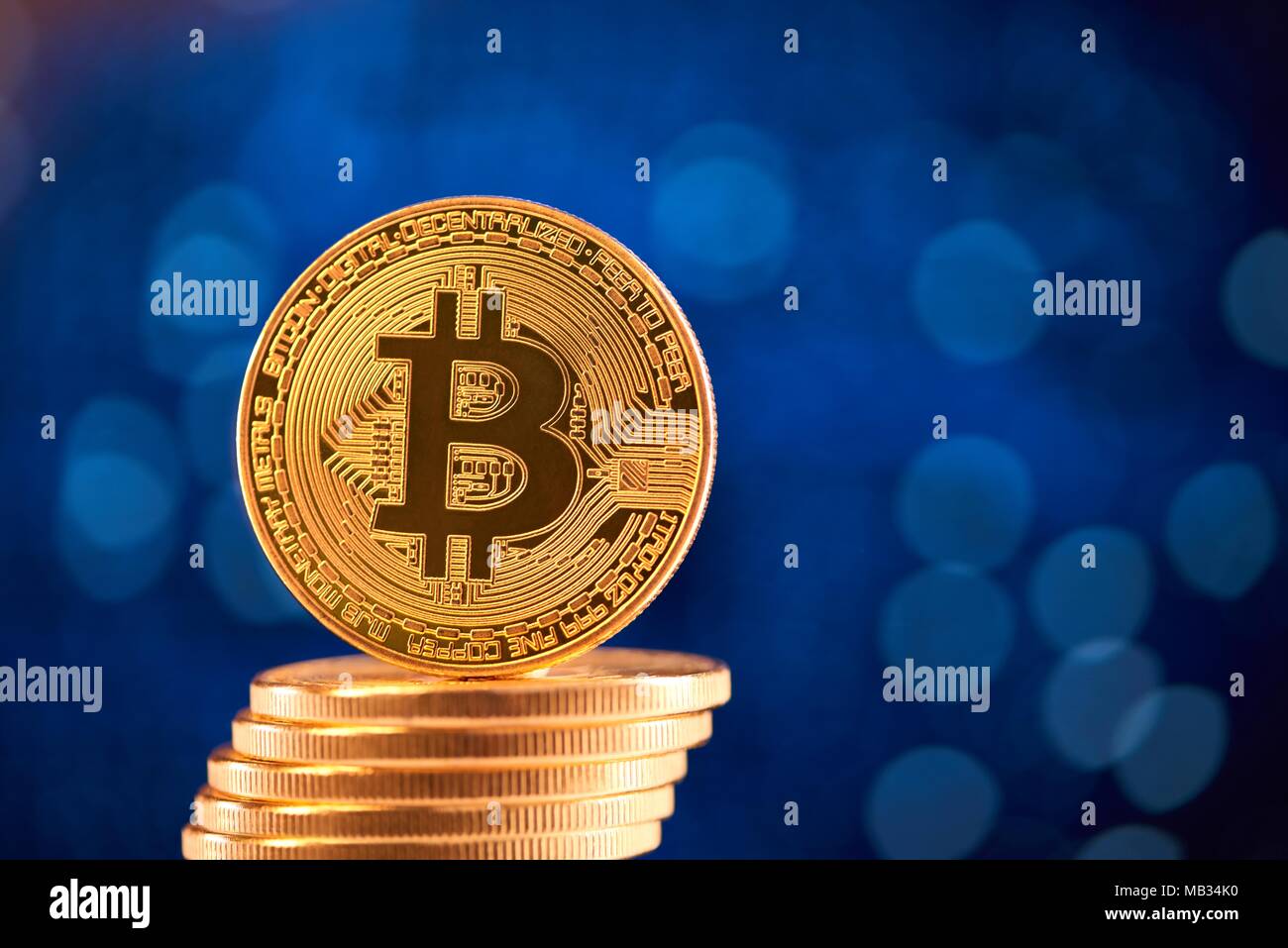 Pile de bitcoins en or avec un bitcoin sur son bord flou placé sur fond bleu. L'argent virtuel numérique blockchain avenir bourse finances bancaires innovantes web business Banque D'Images