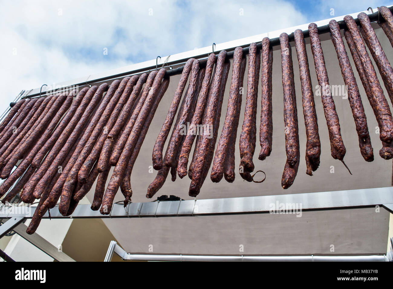 Des saucisses de porc fumé et séché debout sur la table pour la vente. Banque D'Images Des saucisses de porc fumé et séché debout sur la table pour la vente. Banque D'Images