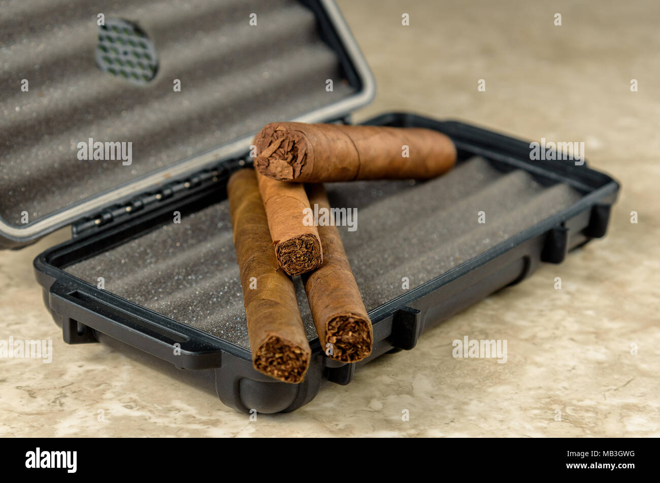 Cigares au-dessus d'un coffret de voyage noir. Odeur riche et textures de feuilles de tabac Banque D'Images