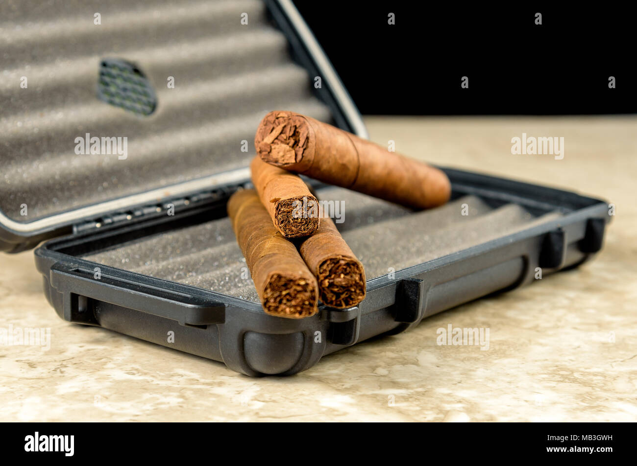 Cigares au-dessus d'un coffret de voyage noir. Odeur riche et textures de feuilles de tabac Banque D'Images