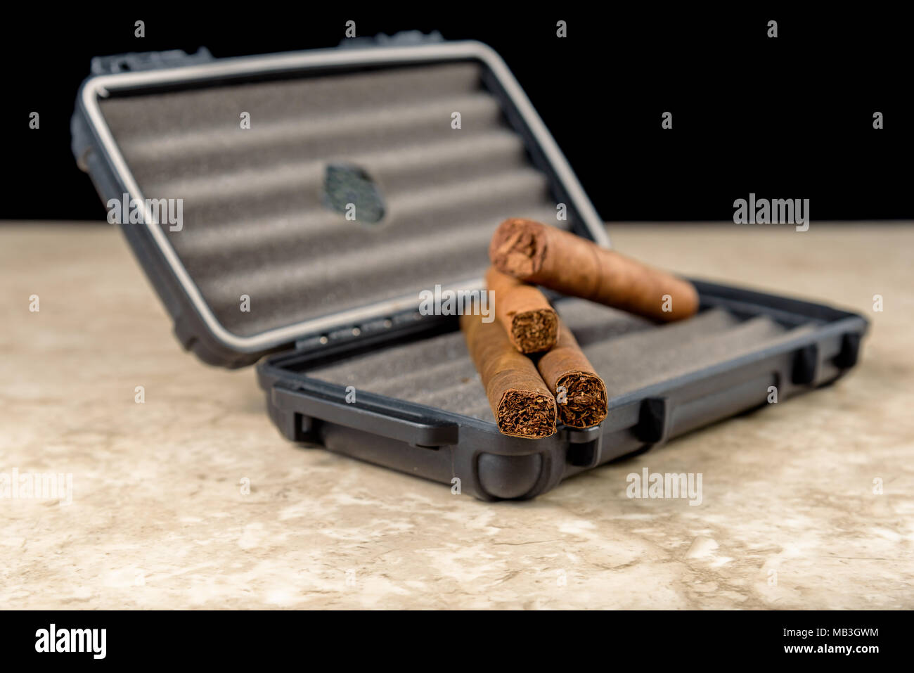 Cigares au-dessus d'un coffret de voyage noir. Odeur riche et textures de feuilles de tabac Banque D'Images