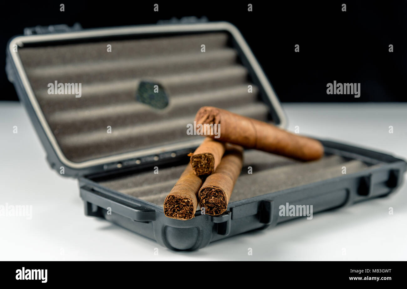 Cigares au-dessus d'un coffret de voyage noir. Odeur riche et textures de feuilles de tabac Banque D'Images
