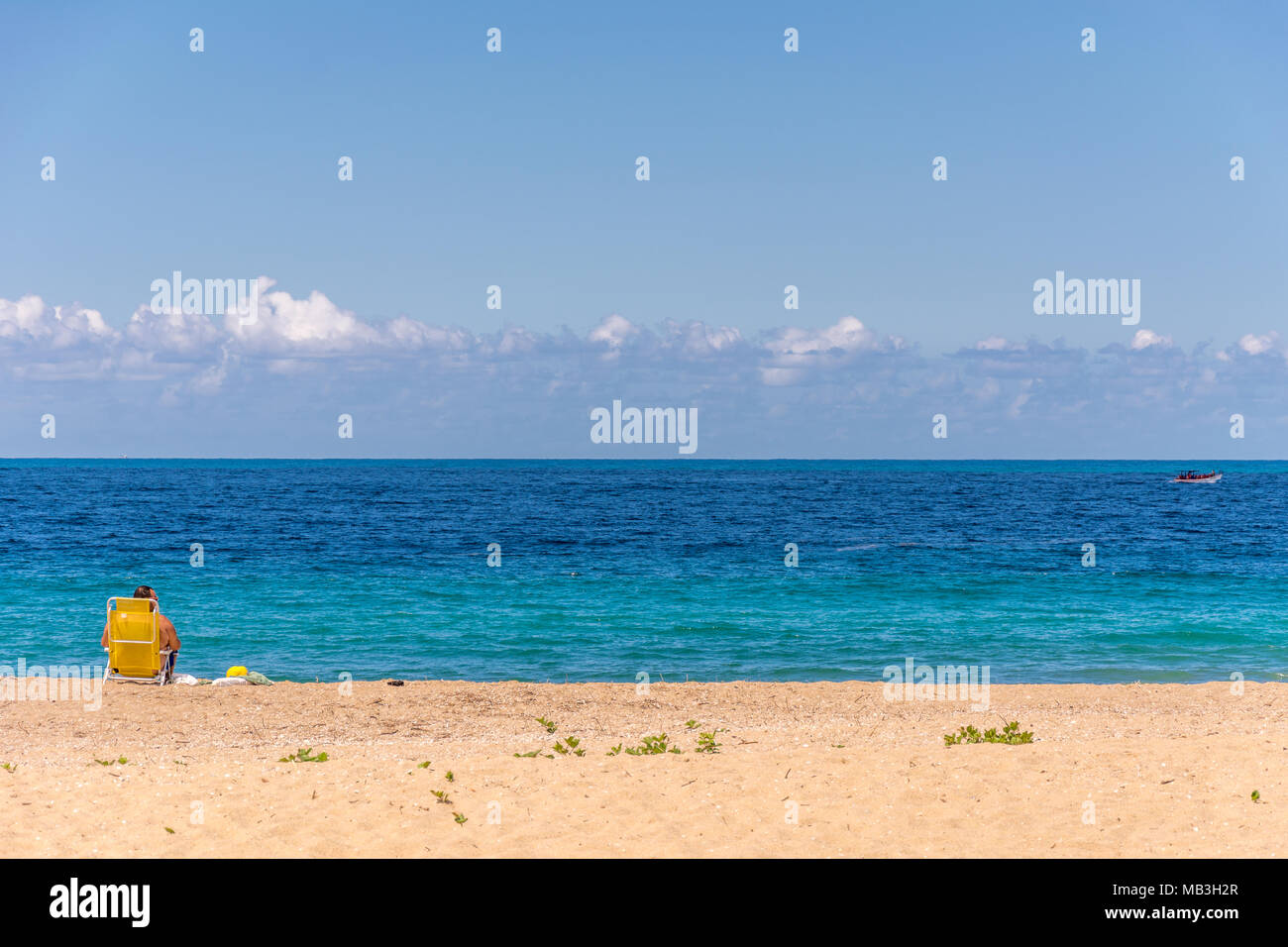 Florianopolis, Brésil. Février, 2018. Tourisme La plage assis sur sa chaise jaune en face d'une mer calme plat. Banque D'Images
