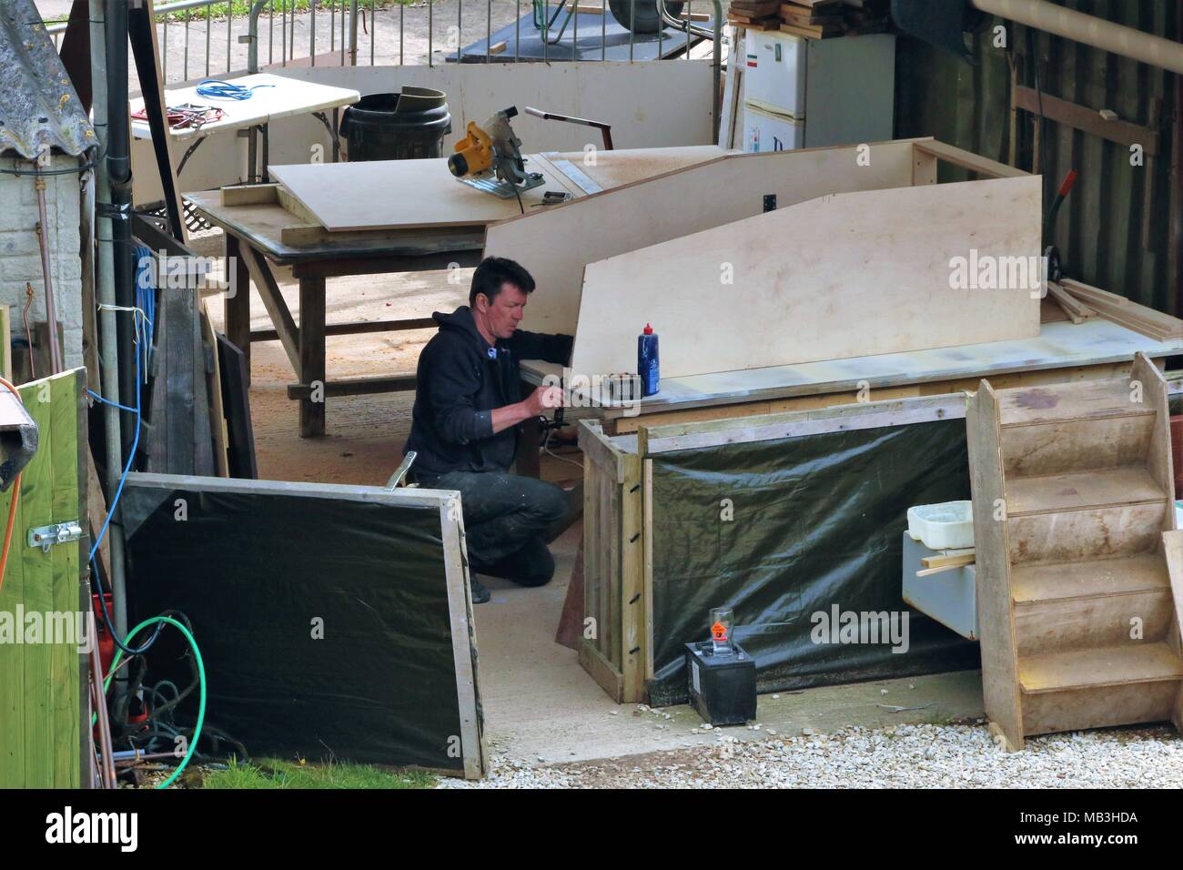 Homme blanc portant des salopettes de travail dans l'arsenal à sec la réparation de bateau à quai Heyford, Oxfordshire, UK Banque D'Images