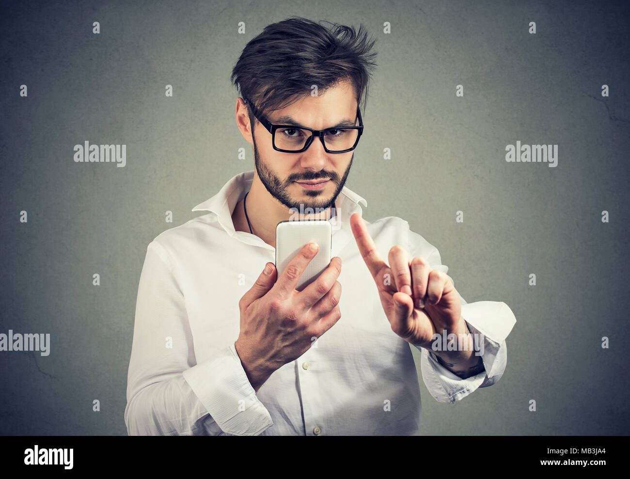 Bel homme à lunettes holding smartphone de se cacher et d'écran montrant la restriction de geste à huis clos. Banque D'Images