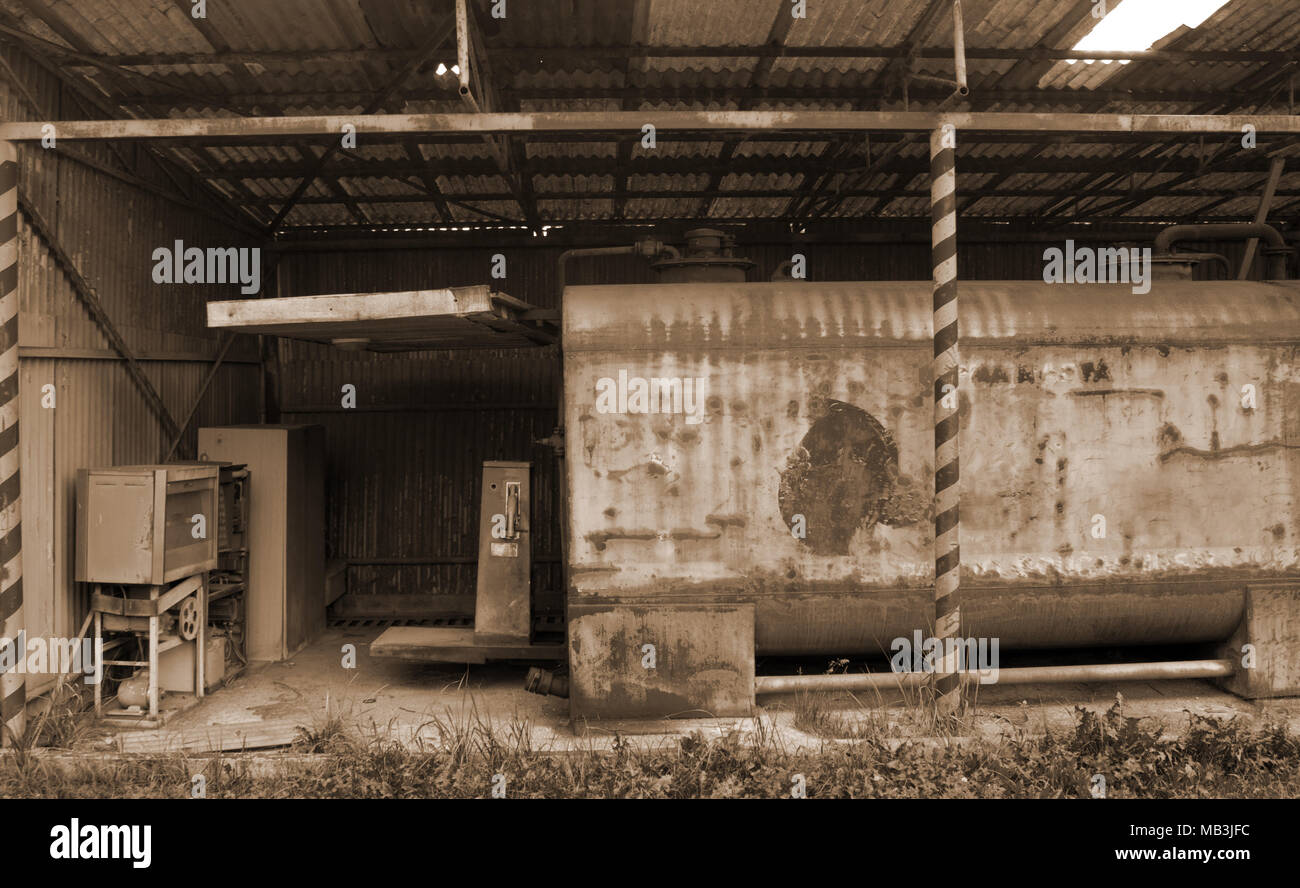 Old rusty permanent de la pompe à essence sous un abri. Au premier plan est l'herbe. Banque D'Images