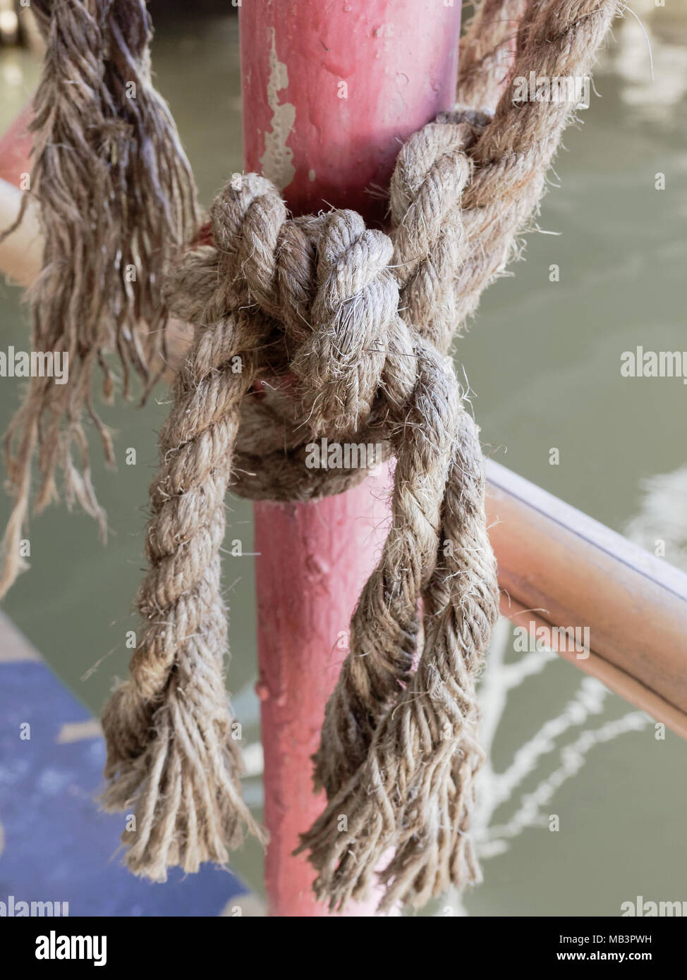 La corde de chanvre attachés ensemble sur mât en acier rouge sur radeau en forme net d'empêcher quelqu'un de tomber dans l'eau sur arrière-plan de la zone rurale Banque D'Images