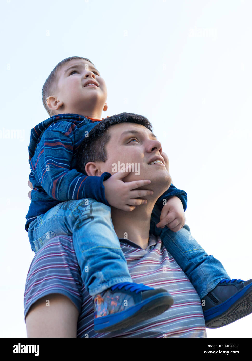 Petit garçon est assis sur les épaules de son père et faire semblant d'un avion au cours de marche dans le domaine Banque D'Images