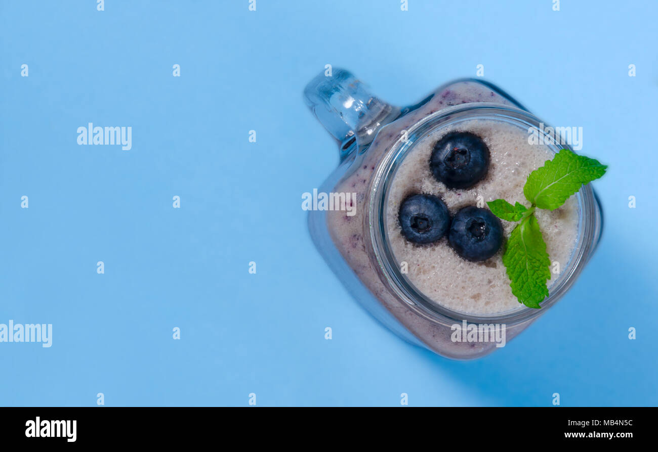 Frappé aux bleuets à la menthe en pot Mason verre avec de petits fruits et de menthe. Voir ci-dessus sur tableau bleu. Alimentation saine. Banque D'Images