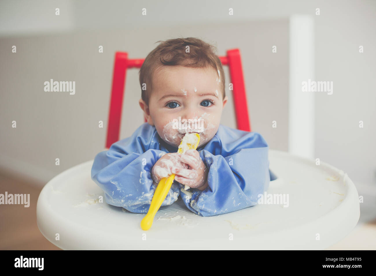 6 mois du garçon se nourrir lui-même le yaourt avec une cuillère Banque D'Images