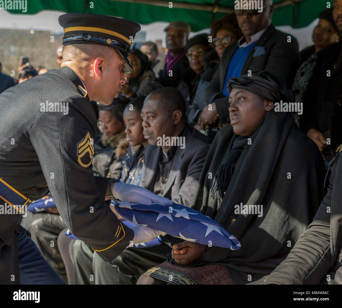 Un soldat de la Garde nationale de l'Armée de New York présente un drapeau américain à un membre de la famille de la FPC. Emmanuel Mensah, lors de ses funérailles au cimetière Woodlawn, Bronx, NY, le 17 février 2018. New York City Fire crédit fonctionnaires Mensah de sauver quatre vies lors d'un immeuble d'un incendie le 28 décembre 2017, le sauvetage des personnes trois fois avant de retourner à l'immeuble et n'est pas sorti. La FPC. Mensah terminé Recherche avancée Formation individuelle à Fort Lee, en Virginie, au début de 2017 décembre, et destiné à servir de véhicule à roues et mécanicien de forage commence avec la Garde Nationale de New York Police Militaire 107e Comp Banque D'Images