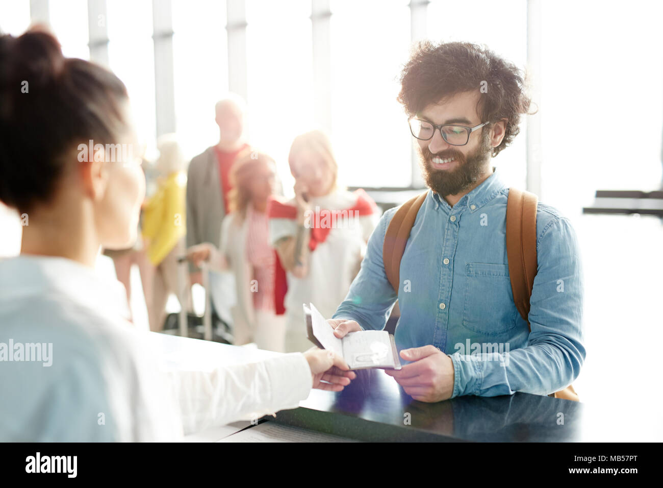 Jeune passager passeport donnant le check-in manager lors de l'enregistrement à l'aéroport avant le vol. Banque D'Images