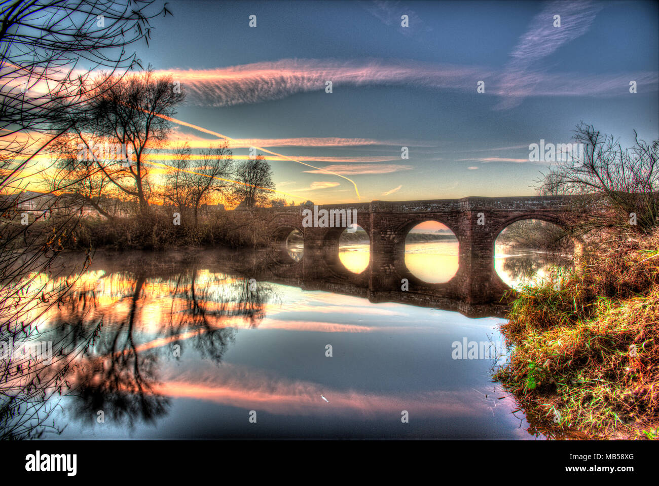 Hespérie de village, en Angleterre. Vue du coucher de soleil du artistique 1 e année 14ème siècle inscrite Holt médiévale Pont sur la rivière Dee. Banque D'Images