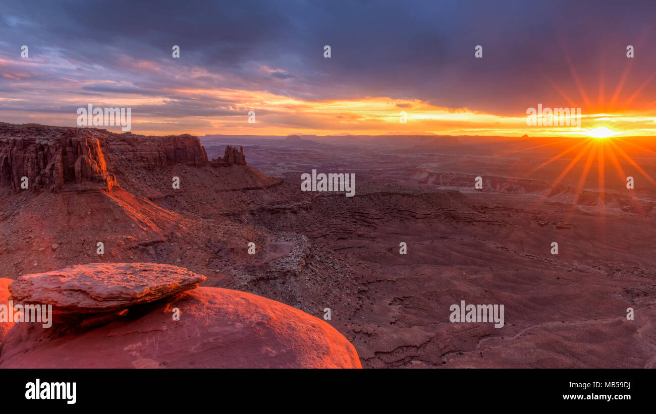 Le soleil qui s'allume et la Butte de jonction dans le ciel de l'île de Canyonlands National Park, en Utah. Banque D'Images