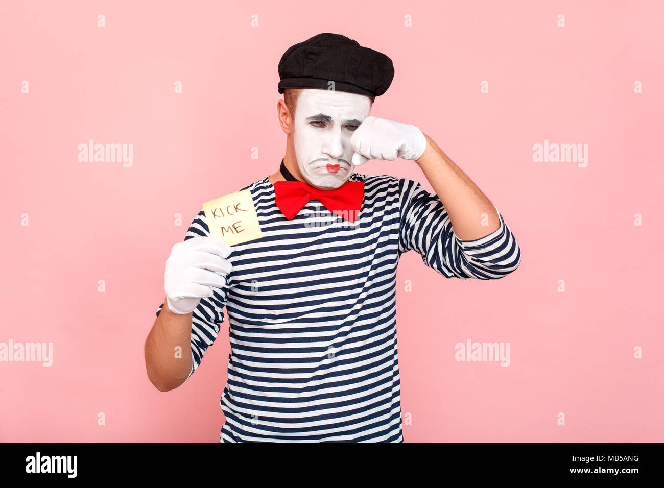 Plaisanterie offensive. L'homme est bouleversée et en larmes. Clown, artiste , mime. Fond rose, Studio shot Banque D'Images