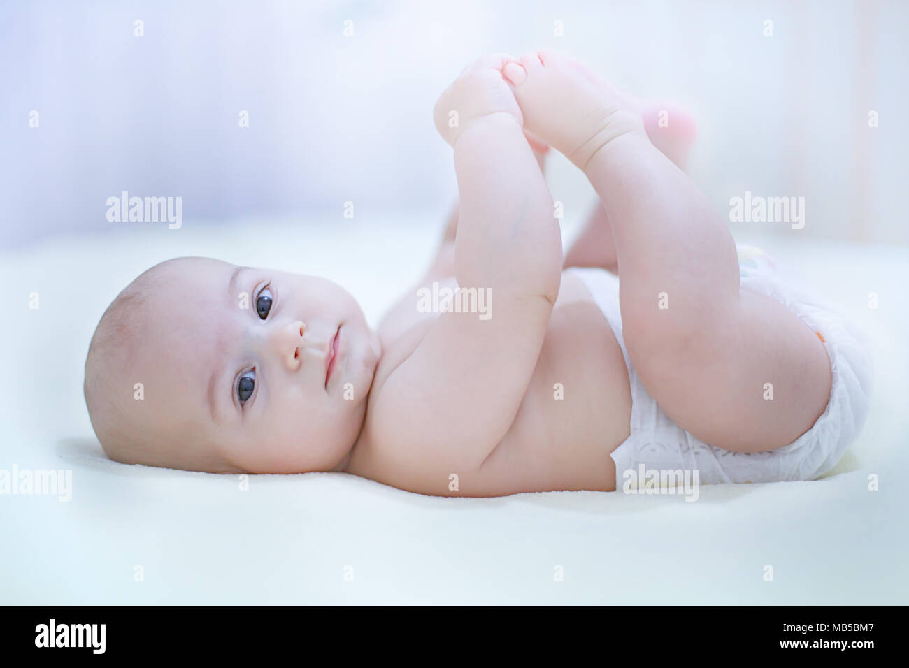 Mignon Bebe Enfant Garcon Portant Des Couches De Jouer Avec Ses Pieds Dans Le Lit Dans Une Chambre Ensoleillee Changement De Couche Pour Bebe Et Les Soins De La Peau Textile Et