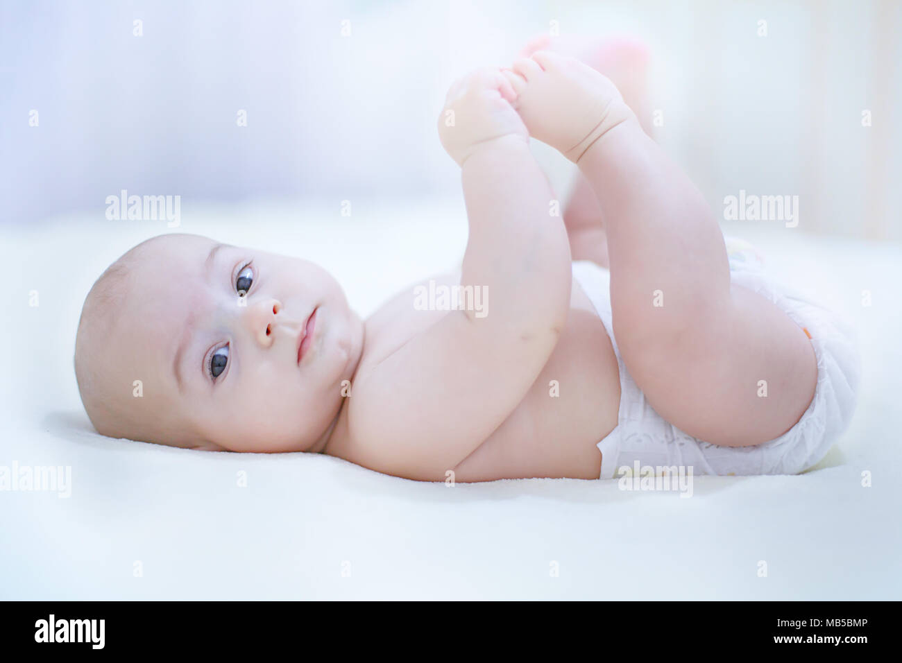 Mignon Bebe Enfant Garcon Portant Des Couches De Jouer Avec Ses Pieds Dans Le Lit Dans Une Chambre Ensoleillee Changement De Couche Pour Bebe Et Les Soins De La Peau Textile Et