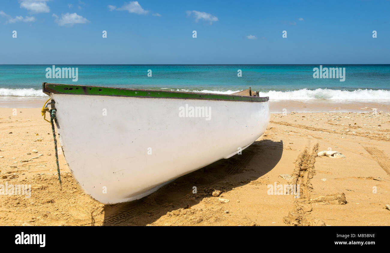 Petit bateau de ligne blanche sur une plage près de bord de l'eau. Banque D'Images