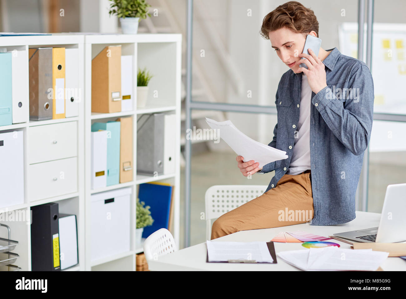 Young businessman avec des documents en mains parler au téléphone Banque D'Images