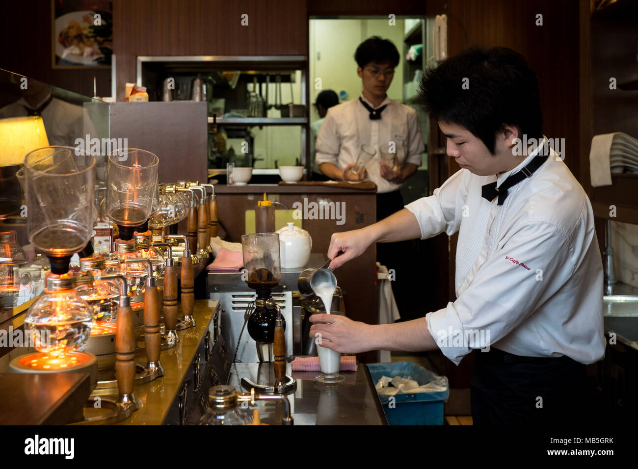 Café Barista avec un syphon cafetière et verser le lait à V Cafe Plaza à Osaka, Japon Banque D'Images