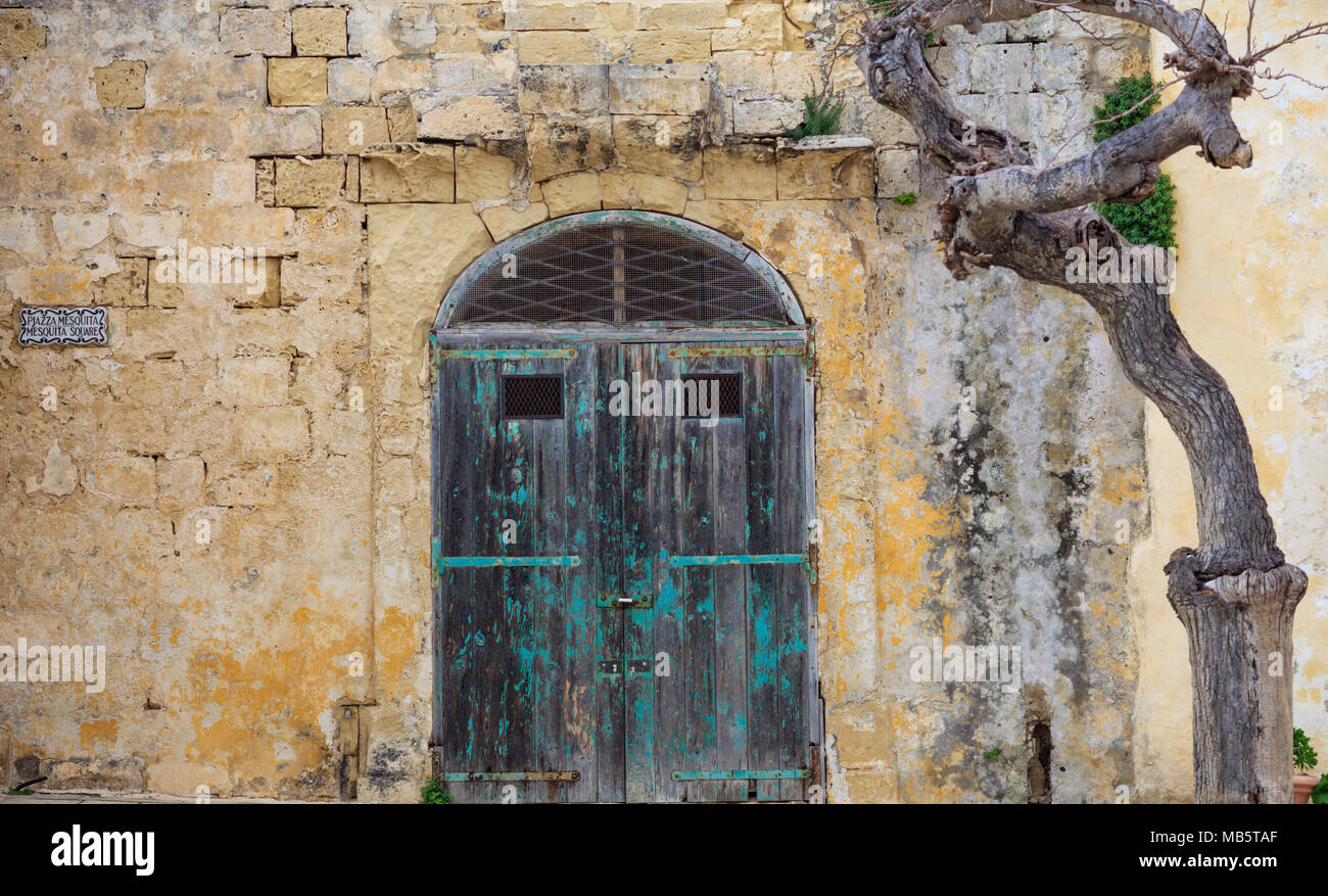 Vieille porte en bois, fermée sur une paroi calcaire jaune. Mdina, Malte, Mesquita square Banque D'Images