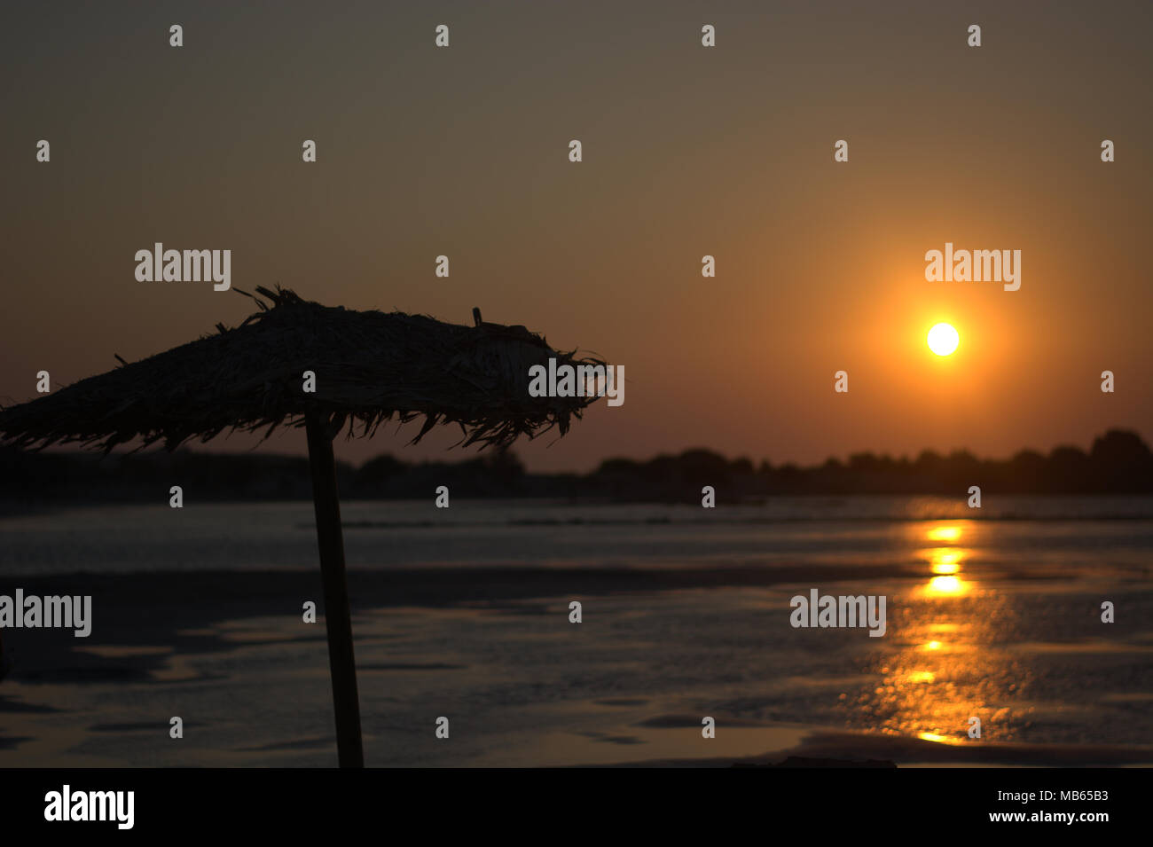 Le coucher de soleil avec un parapluie de paille Banque D'Images