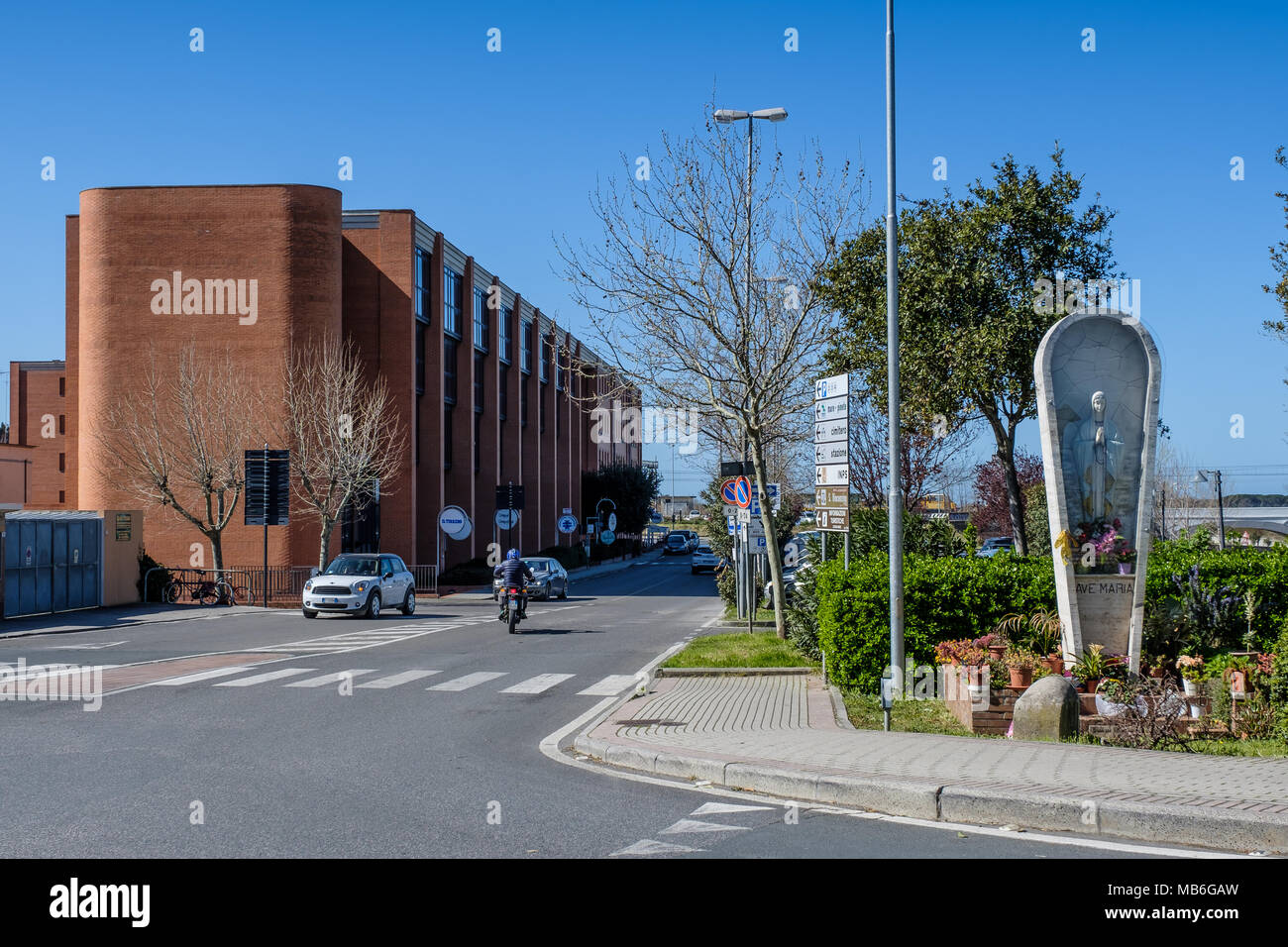 CECINA, Toscane, Italie - 31 mars 2018 : une statue placée à l'entrée de la ville en l'honneur de la vierge sainte et le nouveau palais de briques face vi Banque D'Images