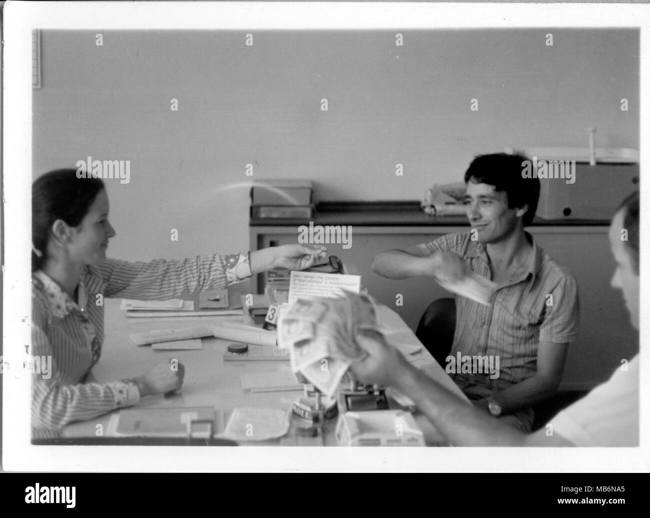 Jeune secrétaire avec son patron à un bureau comptant de l'argent. 1970 noir et blanc. Bureau de l'Italie. Banque D'Images