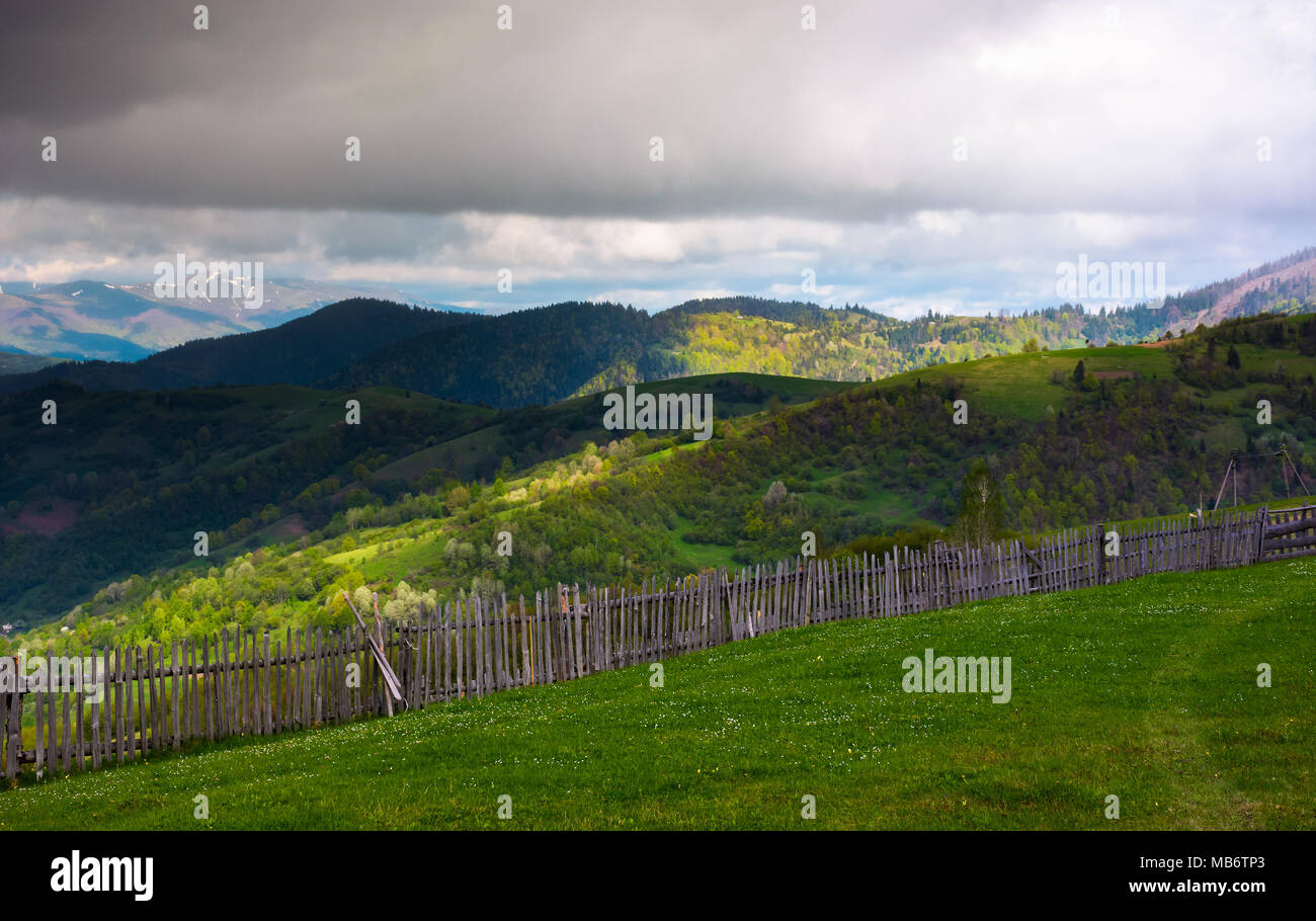 Clôture sur le bord de la colline. beau paysage rural des Carpates au printemps. les collines boisées sous les nuages lourds dans la dista Banque D'Images