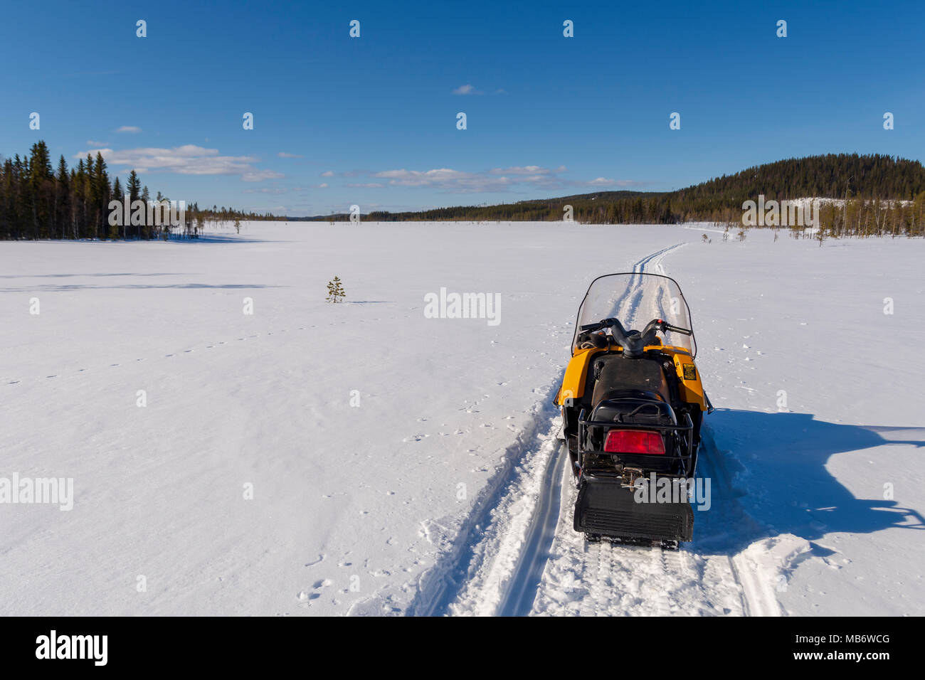 Sur une piste de motoneige sur un bourbier congelé avec une montagne et un ciel bleu en arrière-plan, photo du nord de la Suède. Banque D'Images
