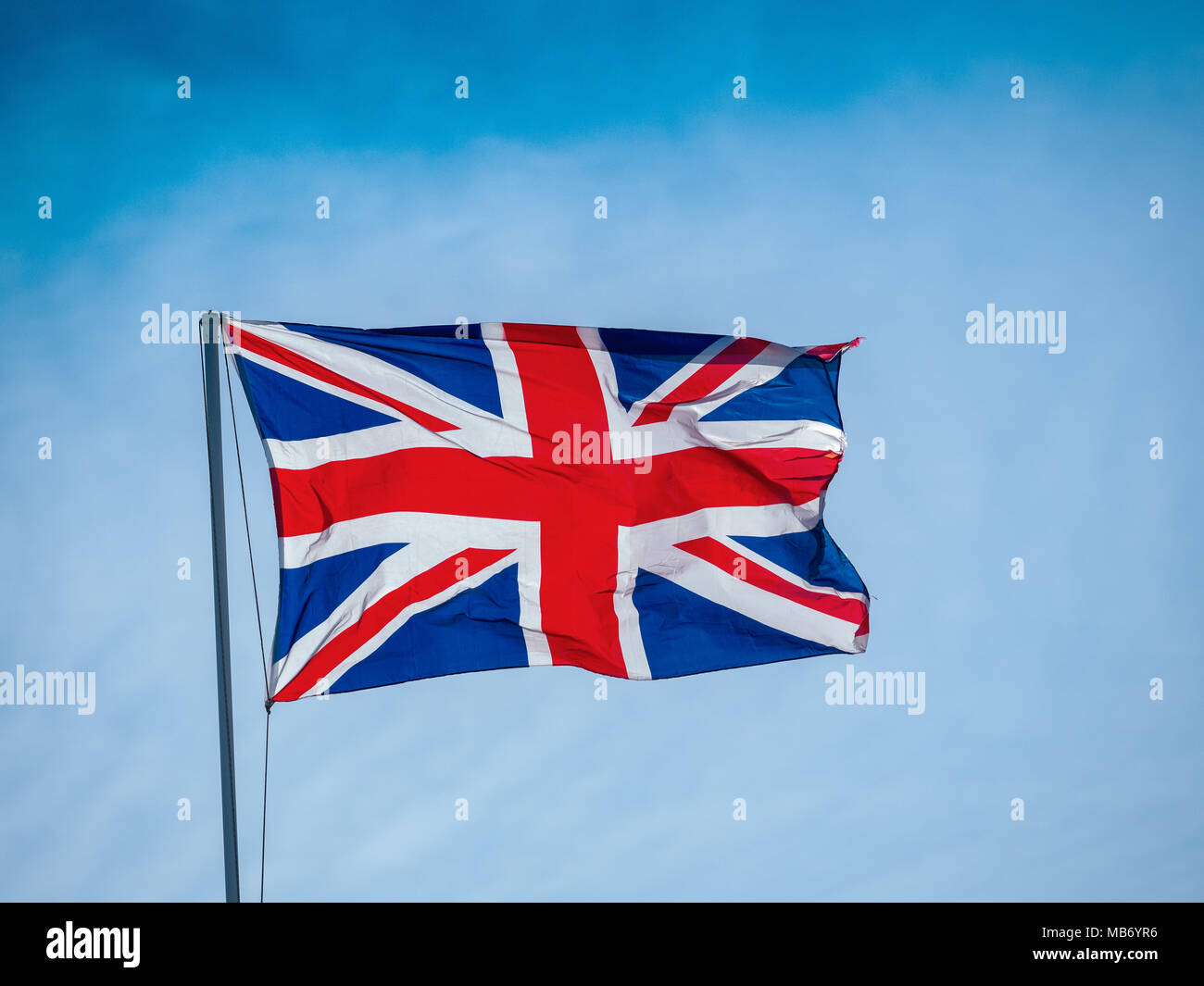 Union Jack Flag contre un ciel nuageux ciel bleu Banque D'Images