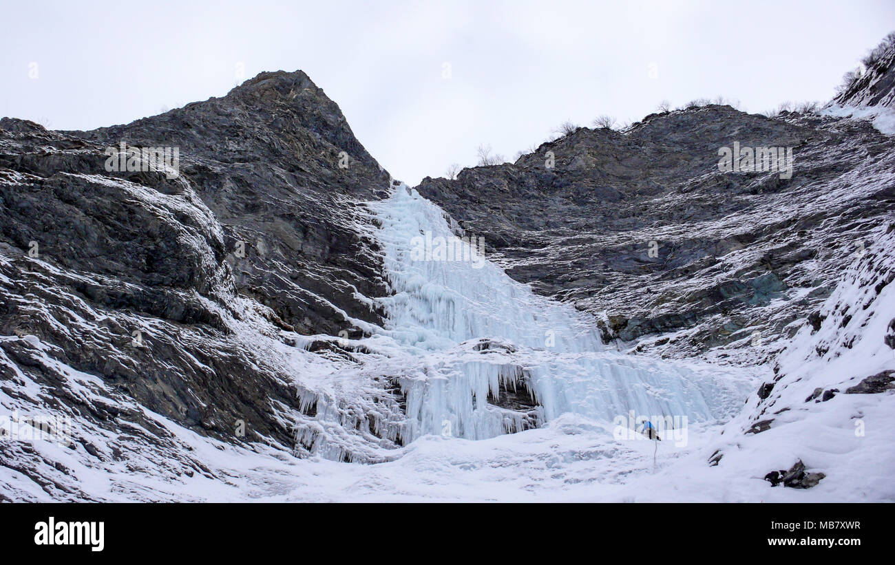 Grimpeur sur glace masculin se dresse à l'headwall d'une longue et raide cascade dans les Alpes Banque D'Images