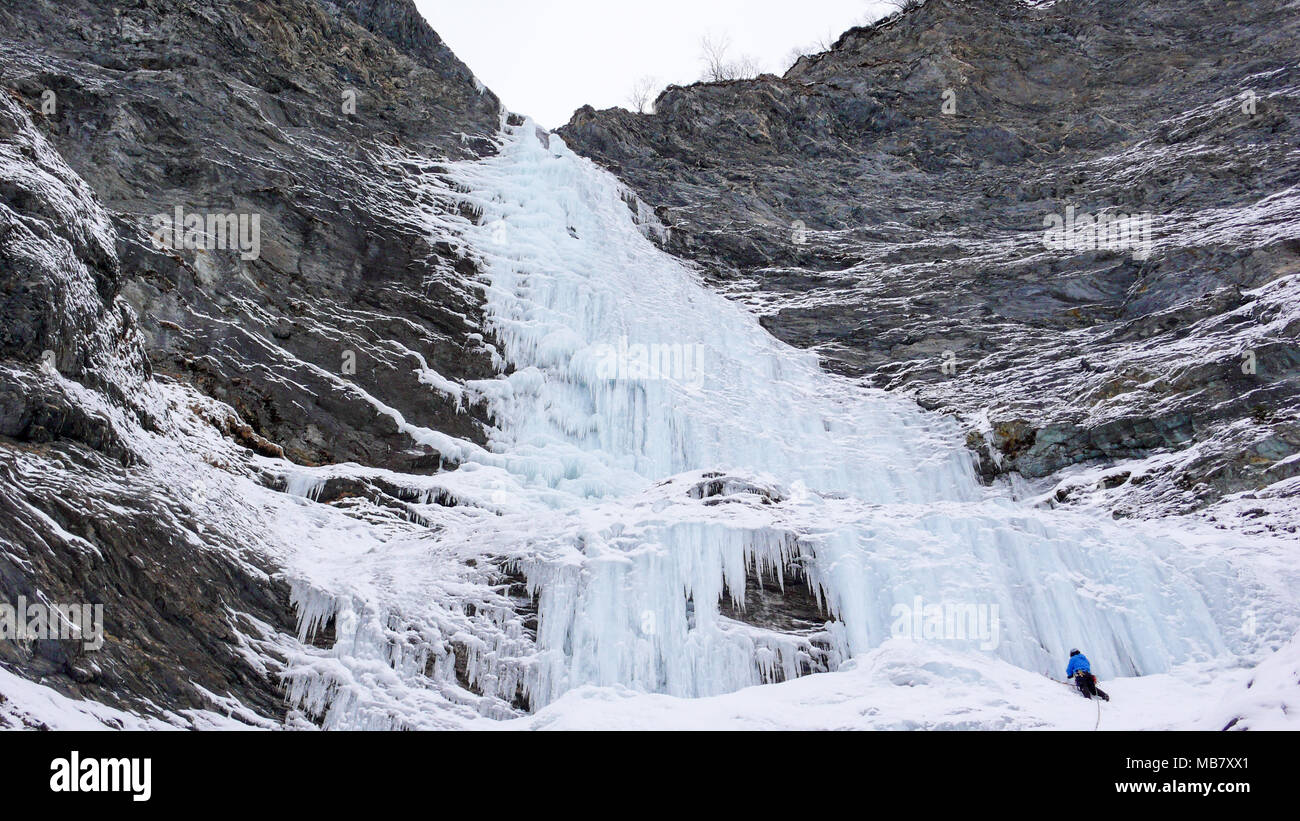 Grimpeur sur glace masculin se dresse à l'headwall d'une longue et raide cascade dans les Alpes Banque D'Images