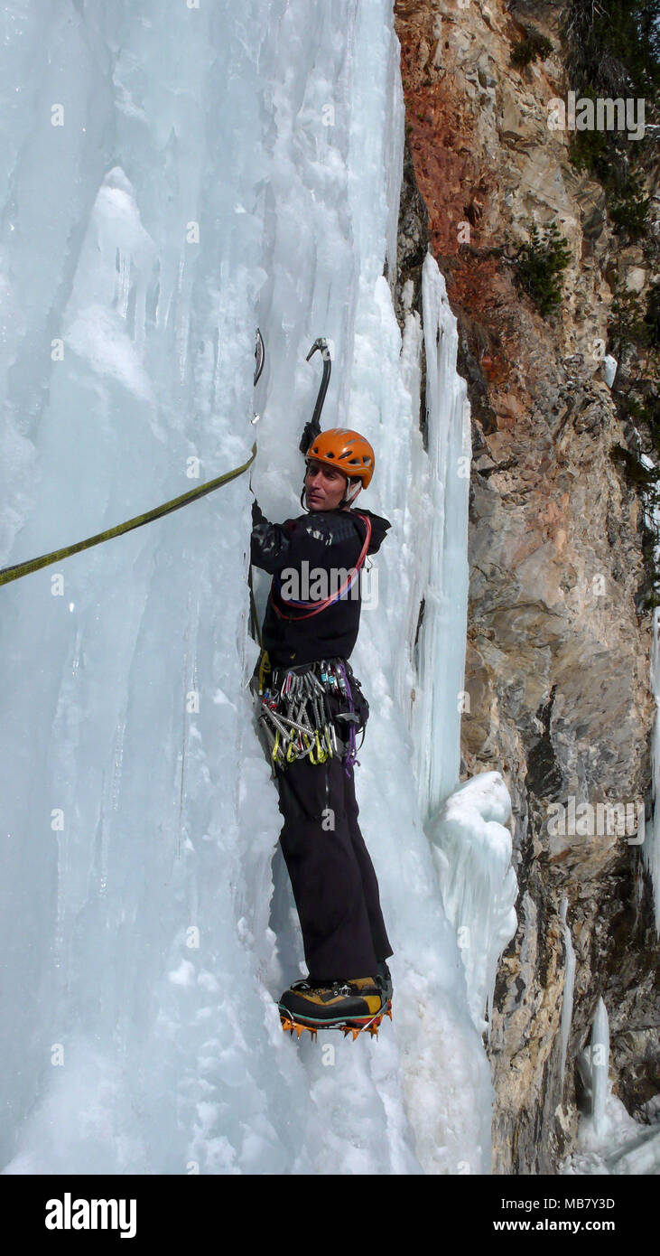 Grimpeur sur glace masculin sur une cascade de glace sur une belle journée d'hiver dans les Alpes Suisses Banque D'Images