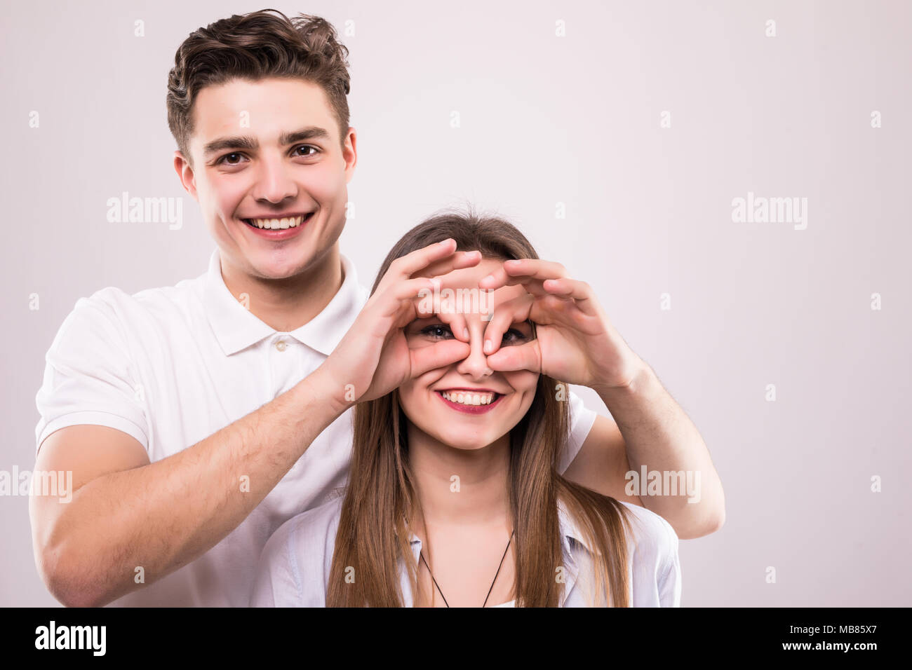 Concept d'avoir funtime et grimaçant, se comportant comme des enfants. La photo en gros plan de deux gens heureux faire jumelles avec leurs mains et montrant langues Banque D'Images